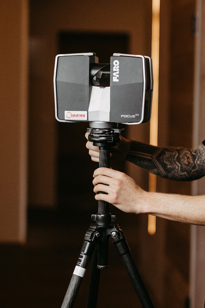 Ein Mann hält eine Kamera auf einem Stativ.