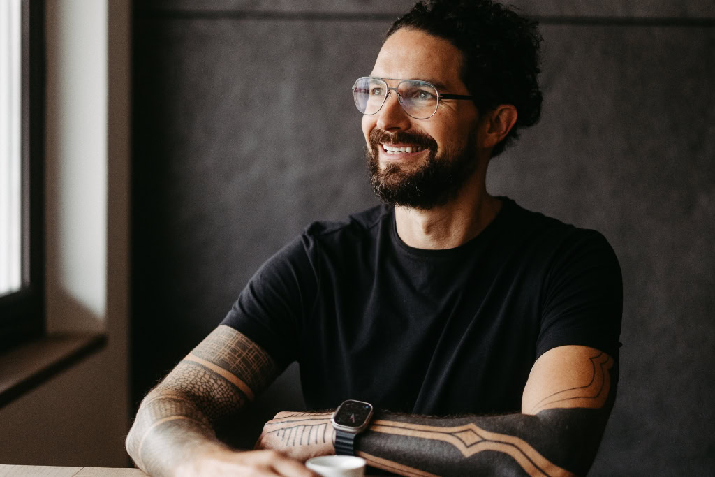 Ein Mann mit Brille und Bart sitzt an einem Tisch.