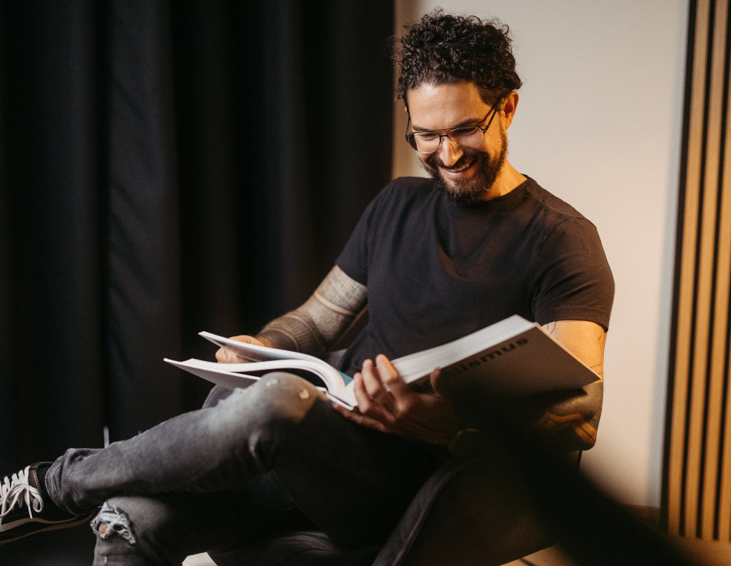 Ein Mann sitzt in einem Stuhl und liest ein Buch.