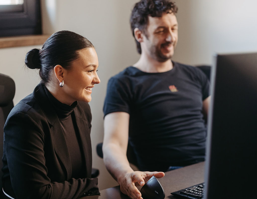 Ein Mann und eine Frau sitzen an einem Schreibtisch mit einem Computer.