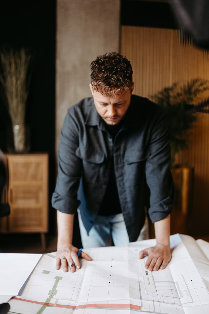 Ein Mann sieht sich einen Bauplan auf einem Tisch an.