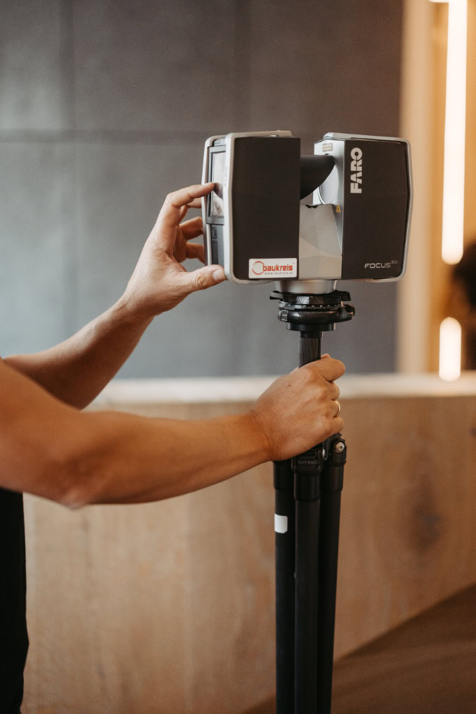 Eine Person hält einen Laser auf einem Stativ.