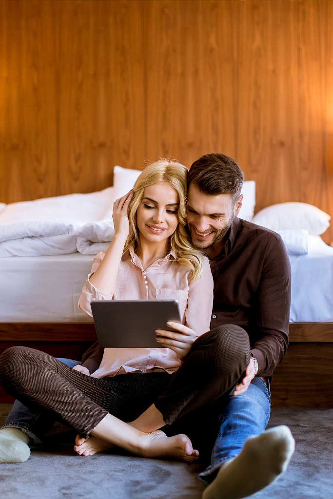 Ein Mann und eine Frau sitzen auf dem Boden und schauen auf ein Tablet.