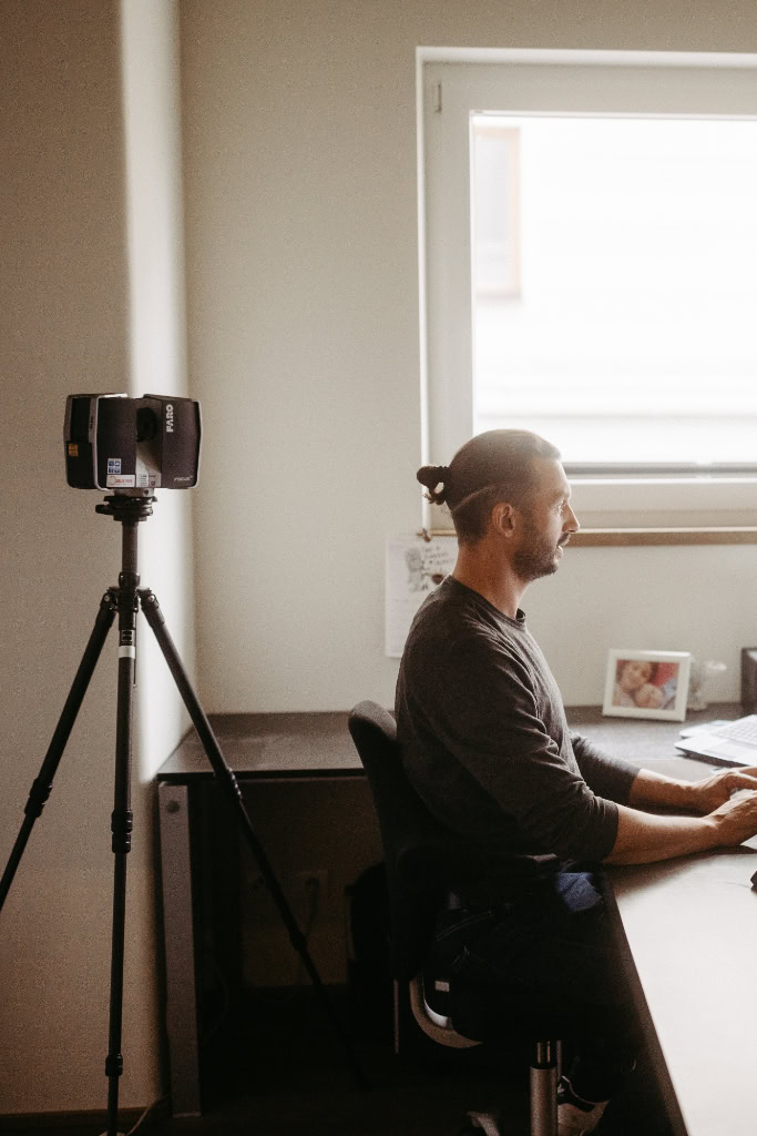 Ein Mann sitzt an einem Schreibtisch mit einem Laptop und einem Laser.